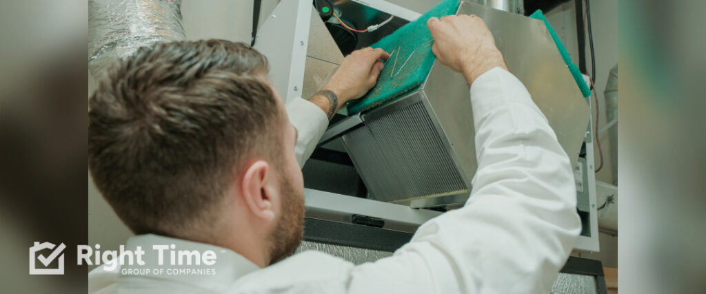 HVAC technician removing a whole-home air filter inside an air handler while checking filtration for allergy-season indoor air quality in Brampton.